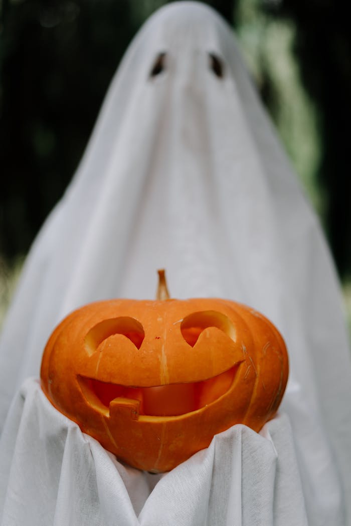 A spooky ghost costume holding a carved jack-o-lantern, perfect for Halloween.