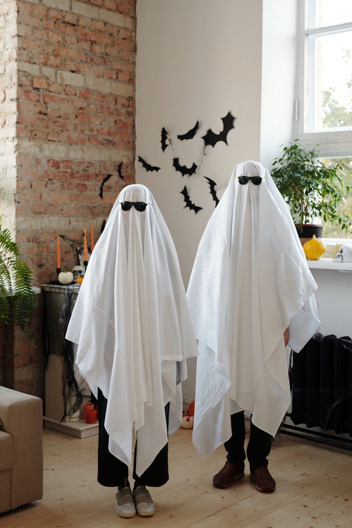 Two people in ghost costumes creating a spooky Halloween vibe indoors.