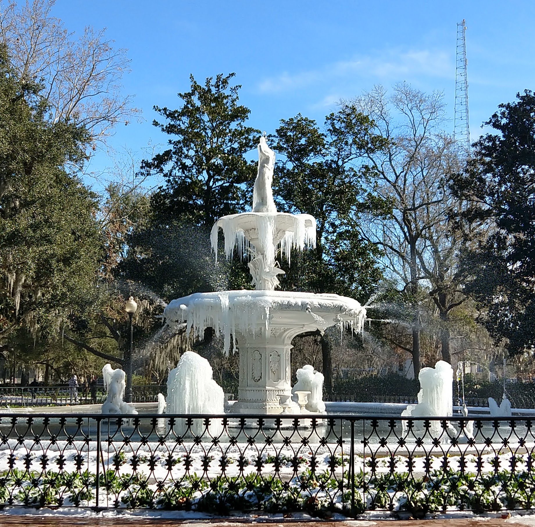 Forsyth Park fountain covered in icicles during the January 2018 Savannah winter storm — water still visibly misting from the upper jets while the structure is encased in ice