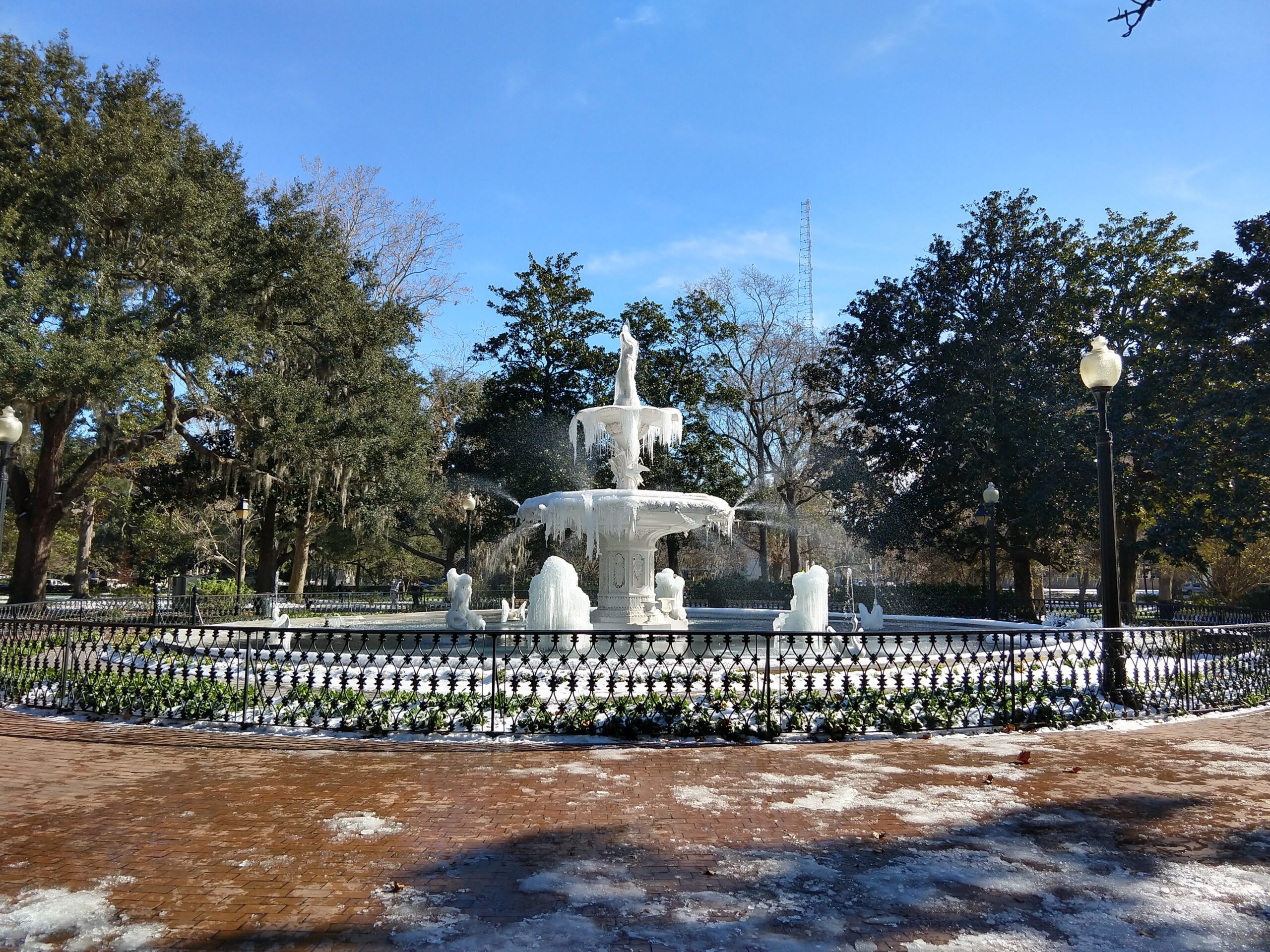 The Forsyth Park fountain frozen solid during a rare winter storm in Savannah, January 2018 — icicles hanging from the cast iron tiers with snow on the ground