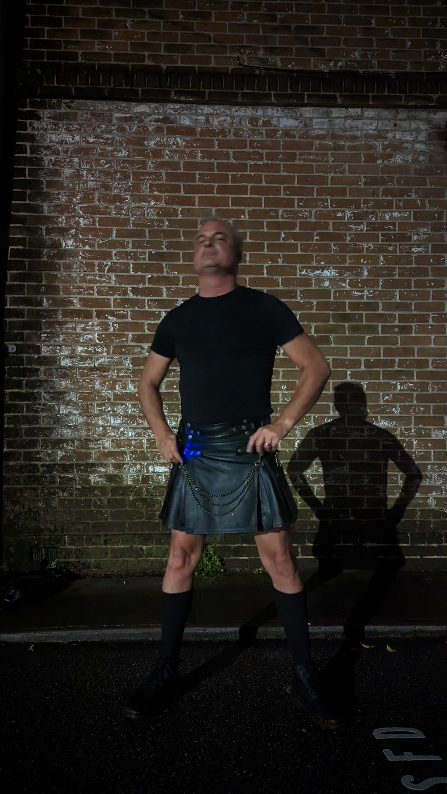 Patrick Burns Savannah ghost tour guide in leather kilt against historic brick wall at night