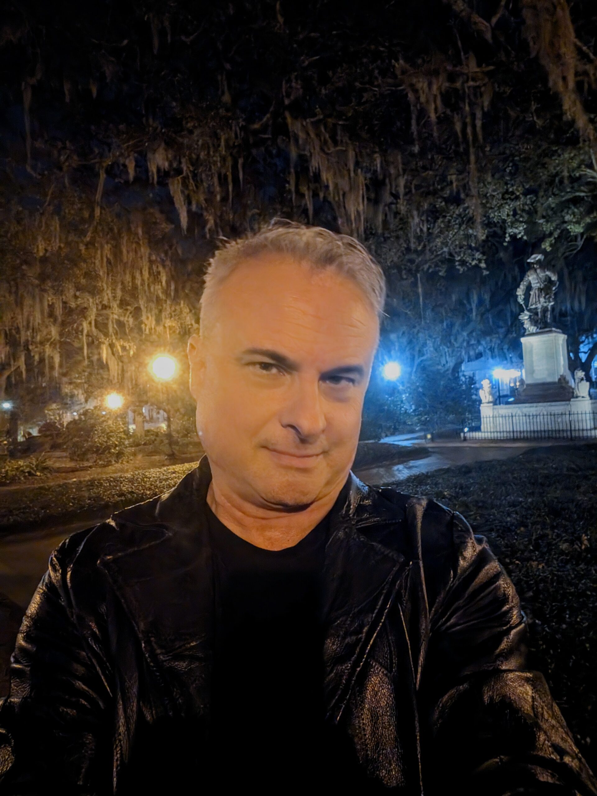 Patrick Burns Savannah ghost tour guide selfie at night in historic square with Spanish moss and statue
